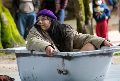 Una actriz con sombrero morado dentro de una bañera en plena actuación