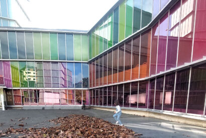 Una niña juega con hojas de árboles caídos junto a la fachada del Museo de Arte Contemporáneo de Castilla y León, Musac, en León