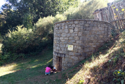 Dos niñas juegan junto a una construcción de piedra, una recreación del antiguo corral de los lobos, una trampa circular para estos animales.