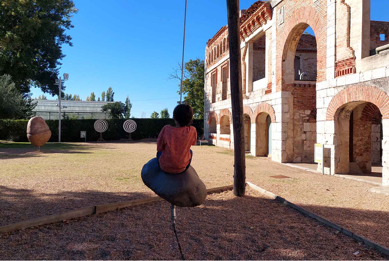 Un niño juega sobre una piedra columpio en el Valle de los Seis Sentidos 